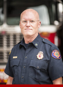 Assistant Chief Sean Daniels standing in front of a fire engine