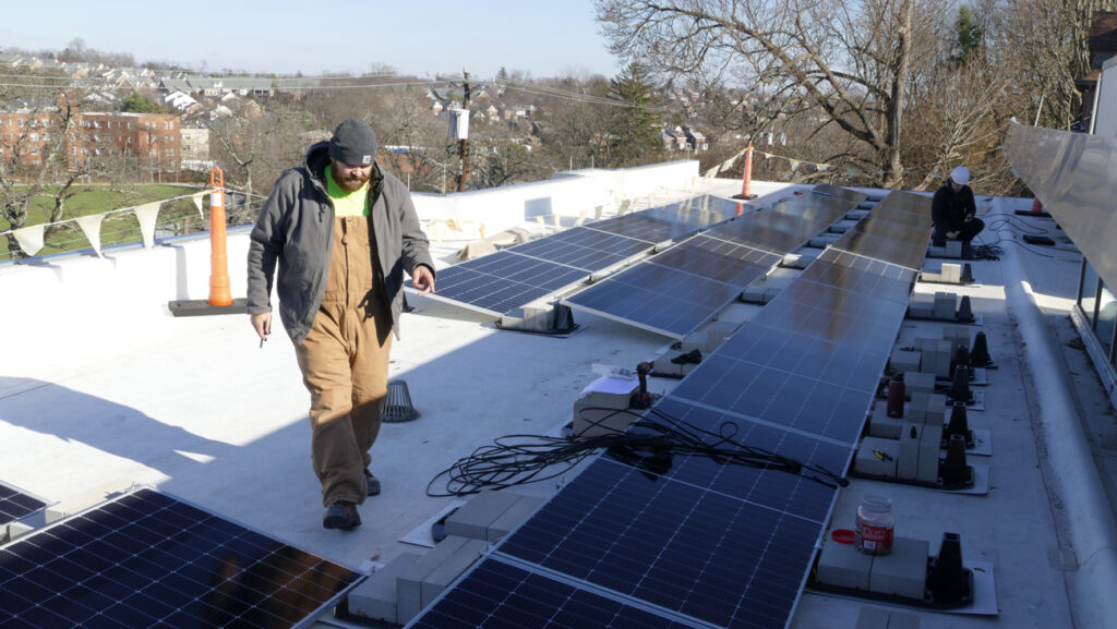Two men installing solar panels on Mt. Lebanon library roof